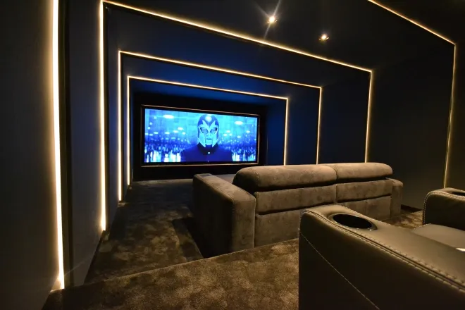 Cine en casa con iluminación lineal LED en paredes y techo y sillas reclinables