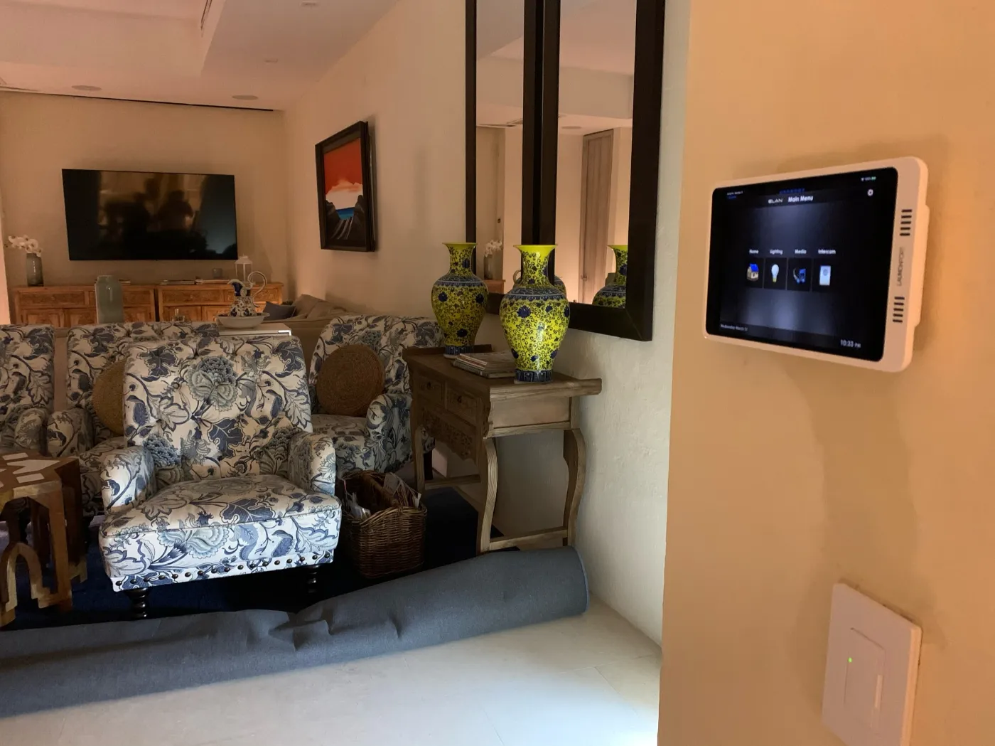 Panel táctil de domótica en pared para controlar iluminación, clima y audio de la sala