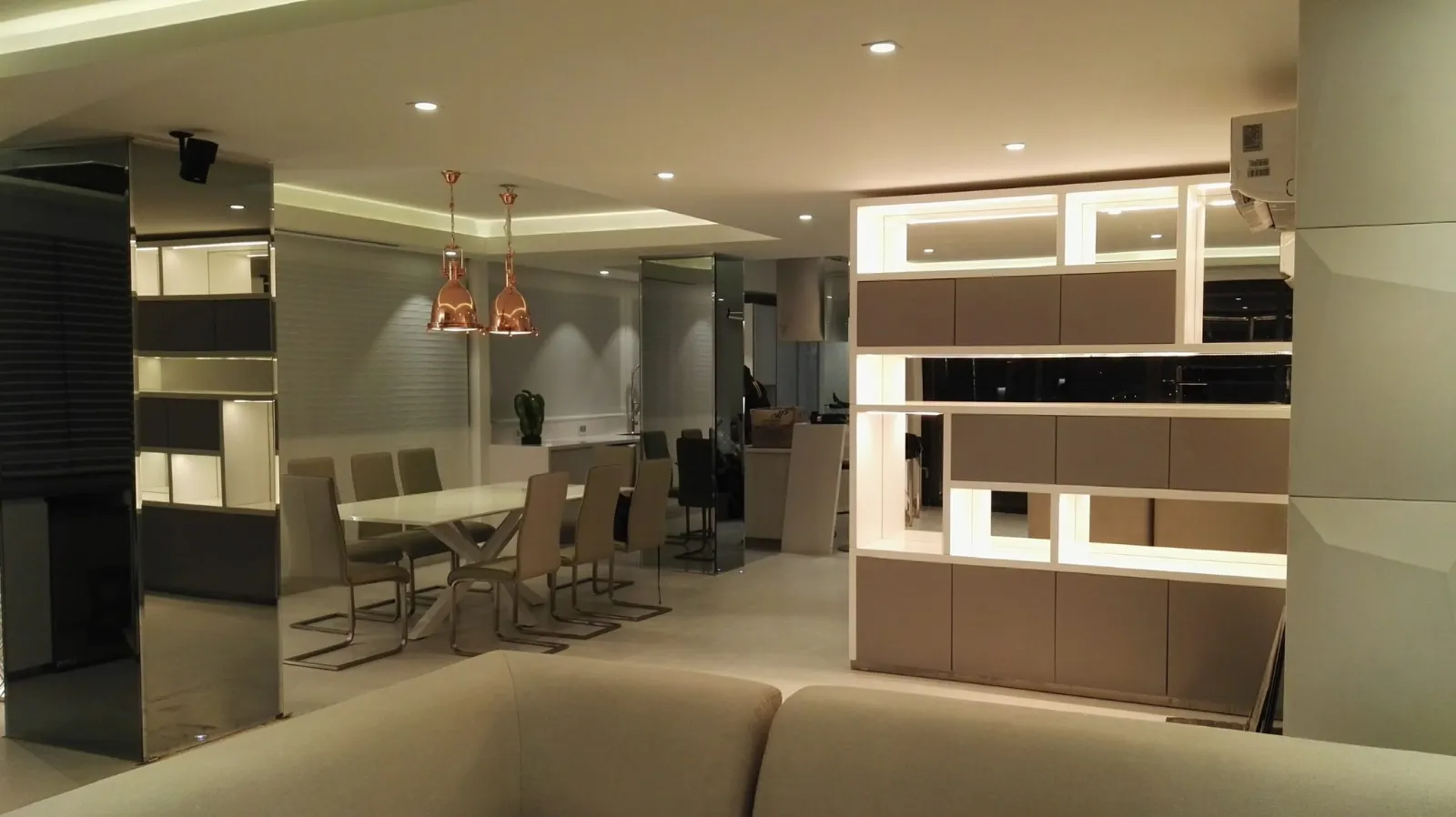 Sala y comedor con iluminación arquitectónica, nichos iluminados y lámparas colgantes